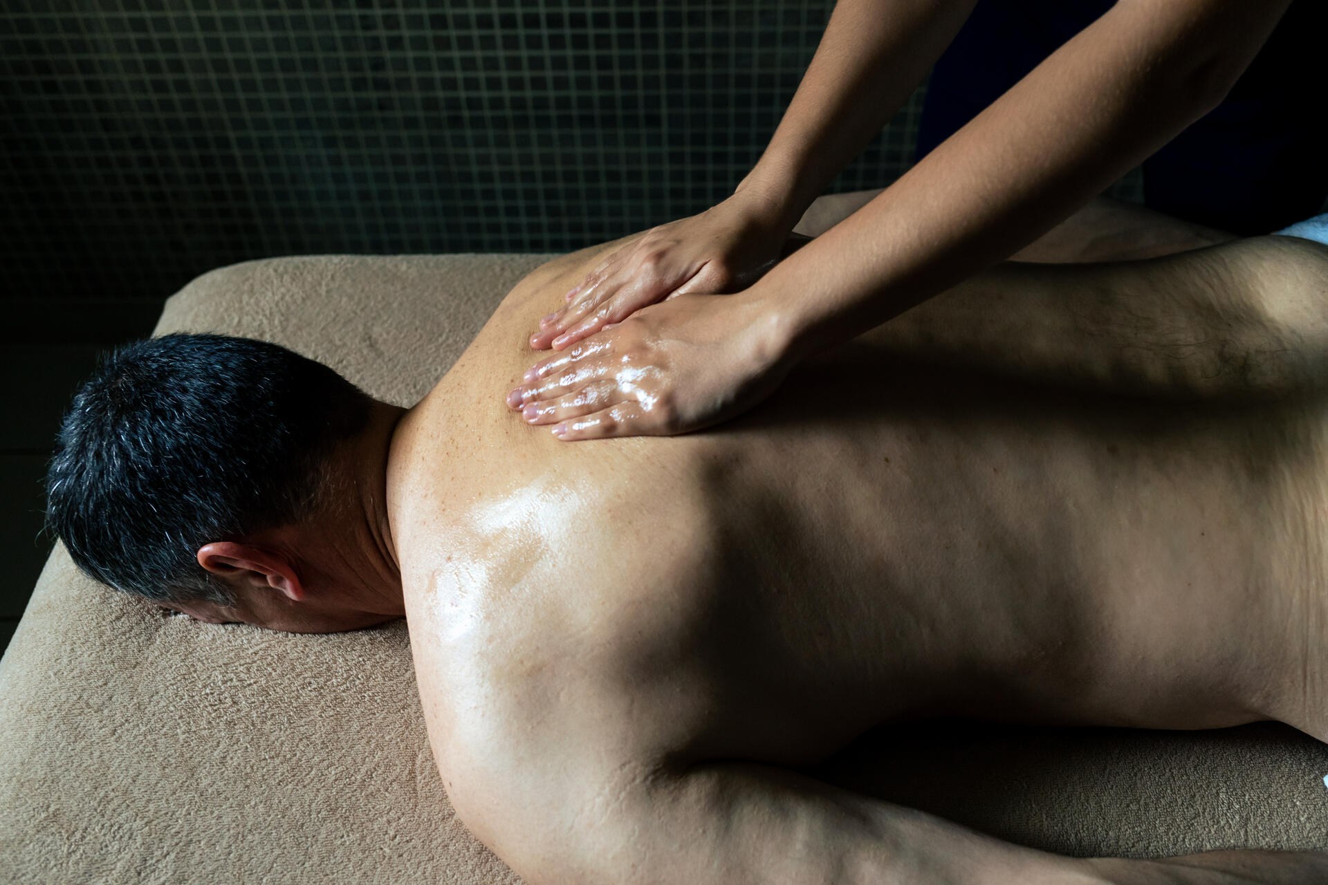 homme se faisant masser le dos sur une table de massage